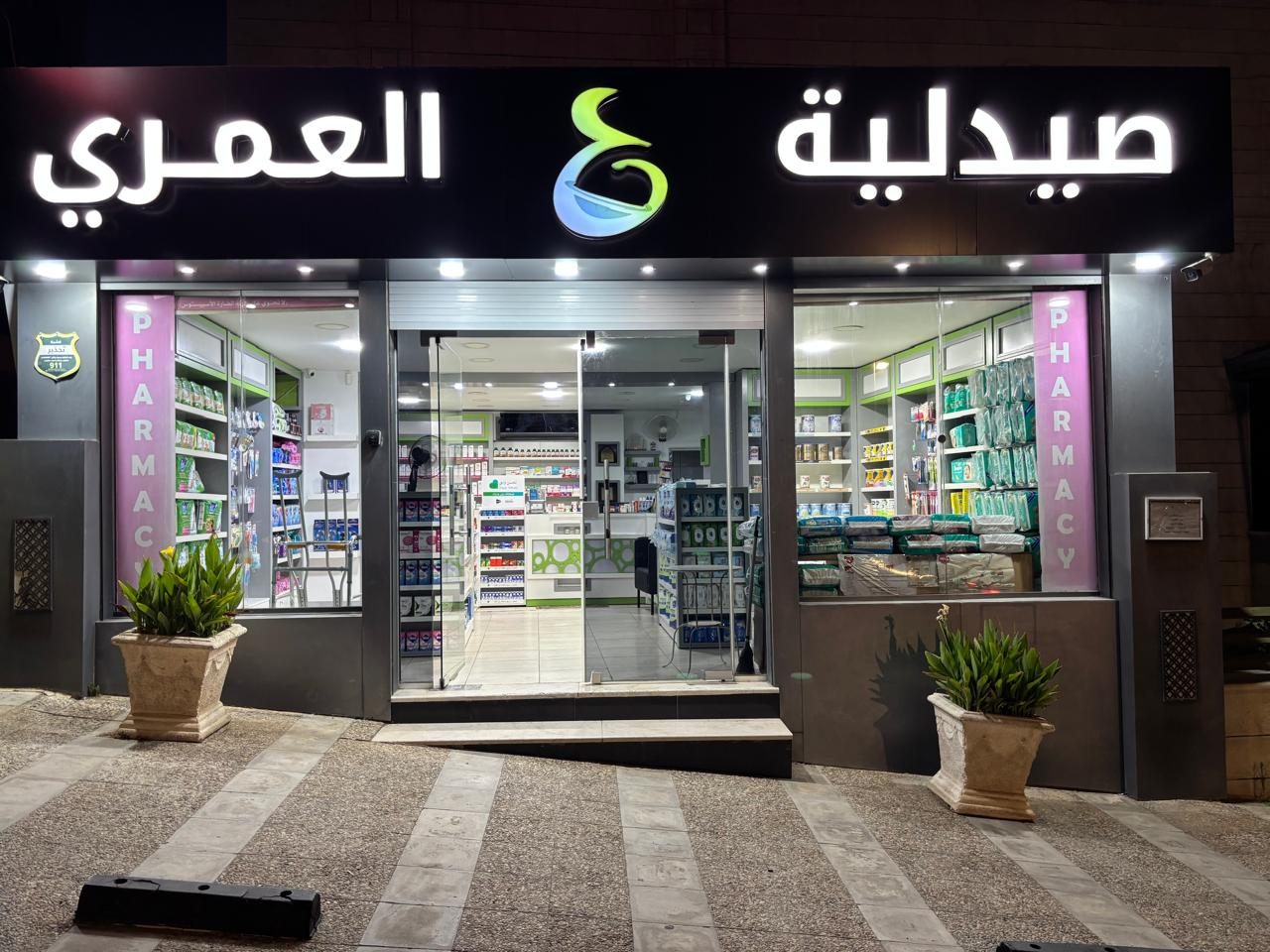 Pharmacy entrance at dusk with illuminated interior shelving